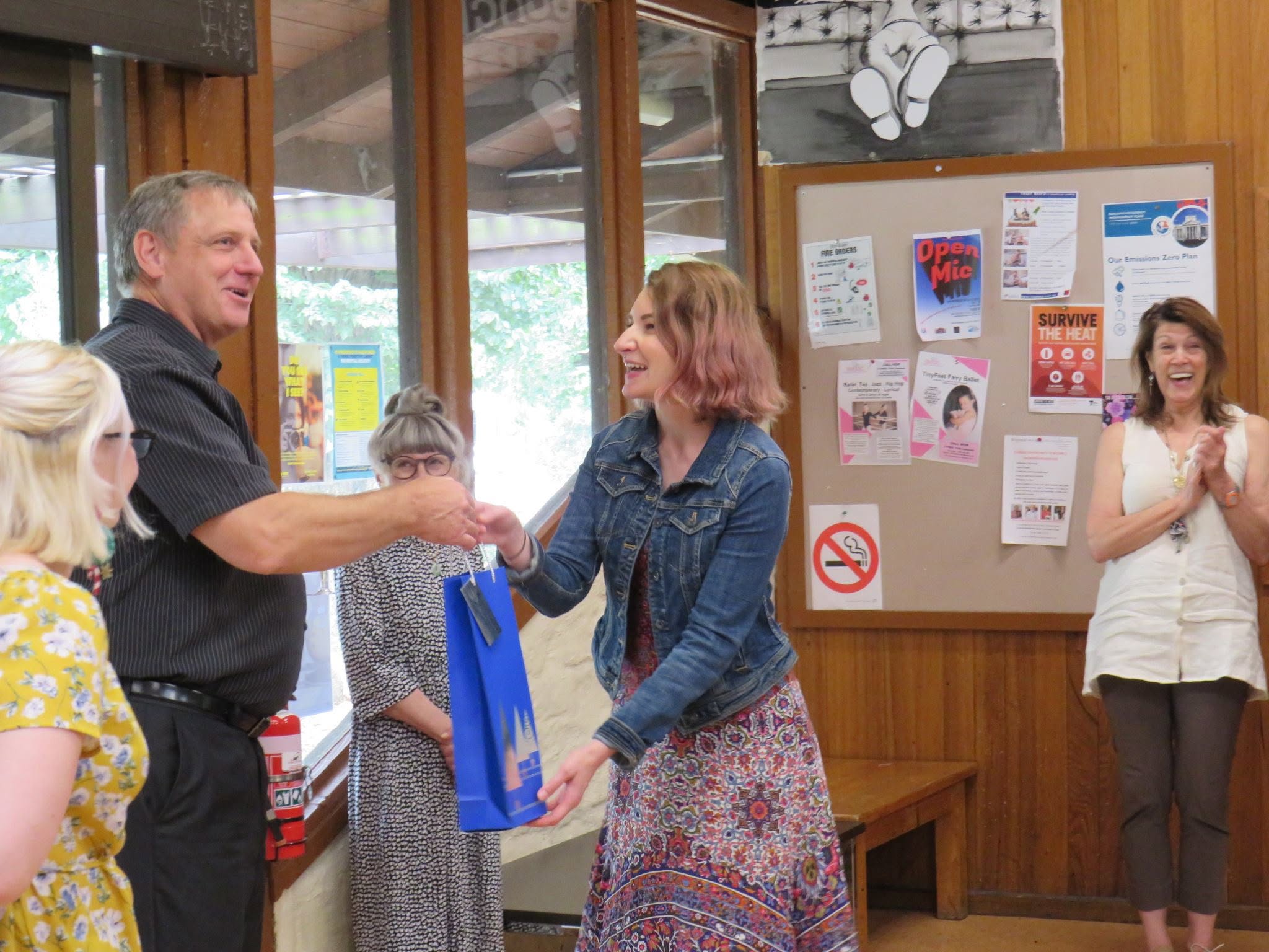 Adults interacting at a community gathering in a wood-panelled room.